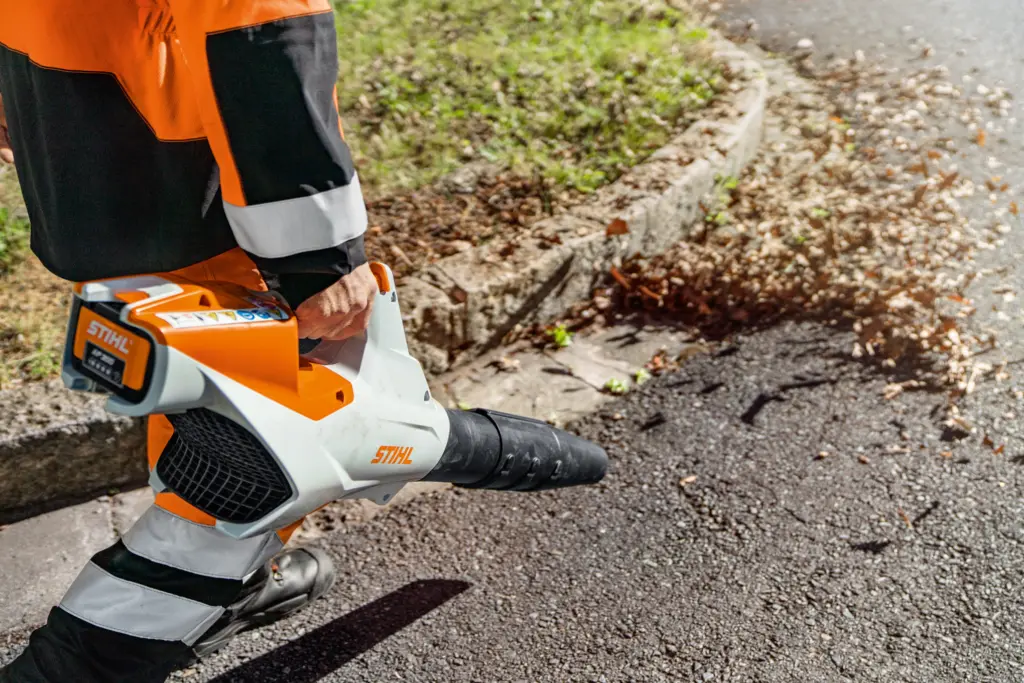 Stihl leaf blower being used on the road by a worker in hi vis