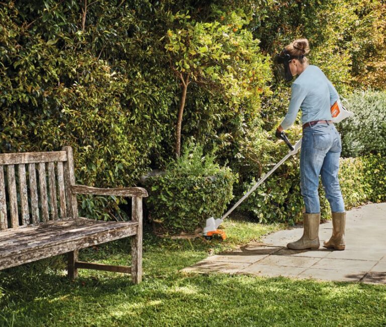 Stihl FSA 57 Cordless Grass Trimmer – Options pictured being used by a woman to trim around a bush