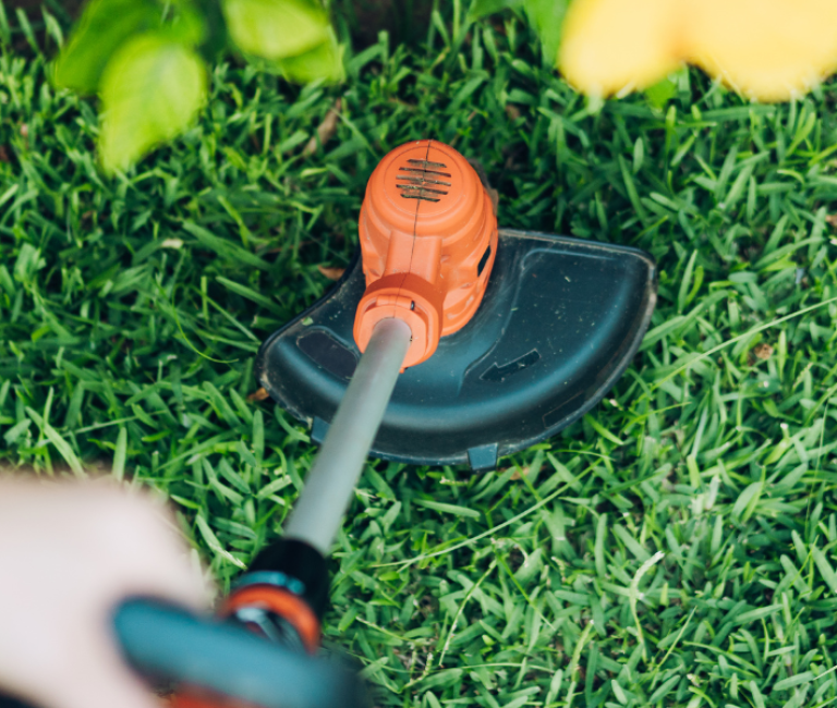 close up of a lawn strimmer being used to cut a lawn